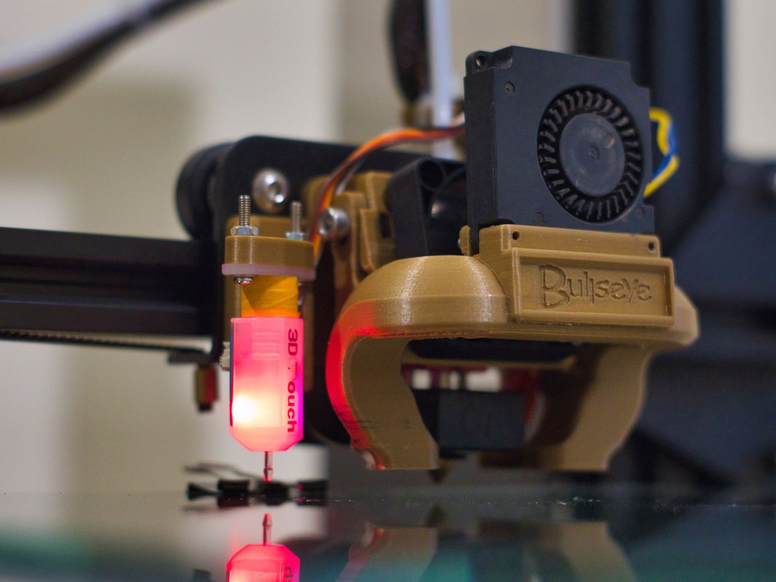 Close-up of an FDM printer nozzle creating a precise technical part in grey material.