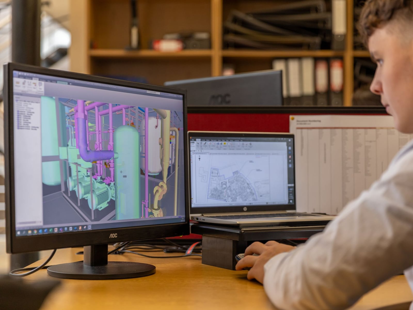 Professional engineer designing a technical 3D model using CAD software in the studio.